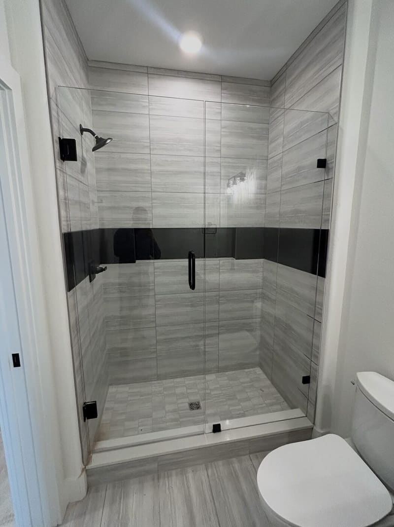 Large frameless glass shower with dark tile accent stripe